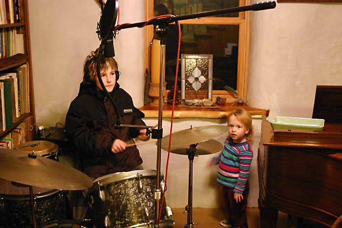 Zac playing drums with Lucy watching