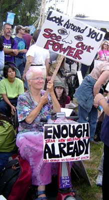 Woman with signs saying  "Look Around You and See Our Power" and "Enough Already"