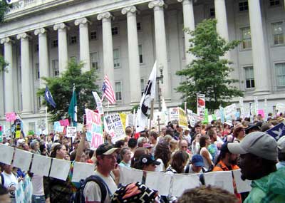 Big crowd of marchers passes a big government building.