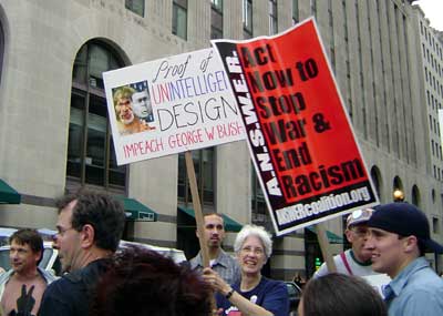 Sign says "Proof of Unintelligent Design - Impeach George W. Bush"